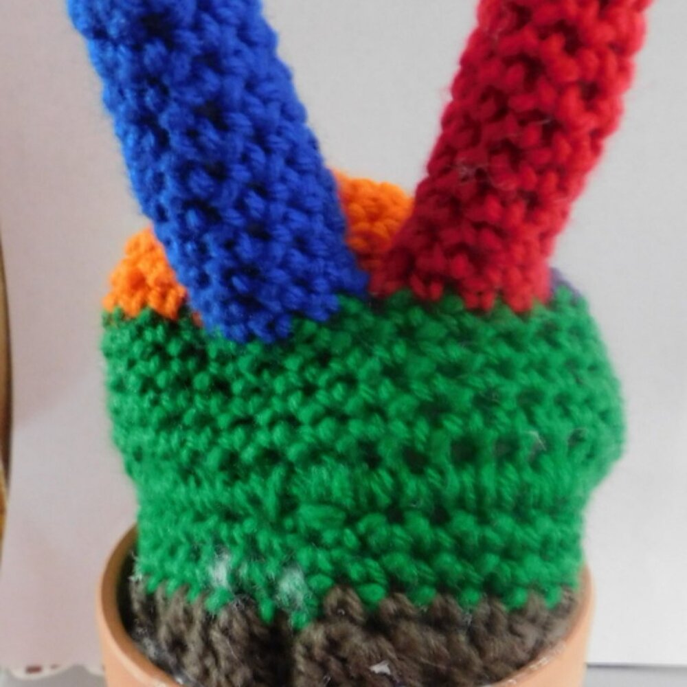 Crocheted rainbow color finger peace sign cactus in clay pot